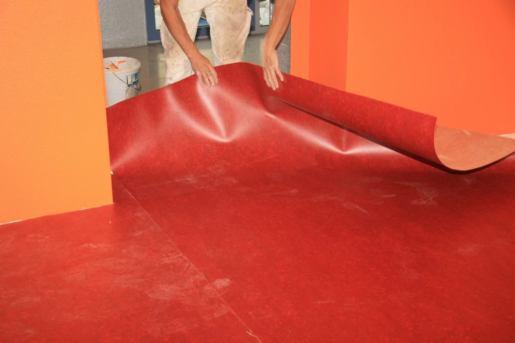 Roter PVC-Bodenbelag wird in Türrahmen eingepasst, Anschluss an fertige Bahn